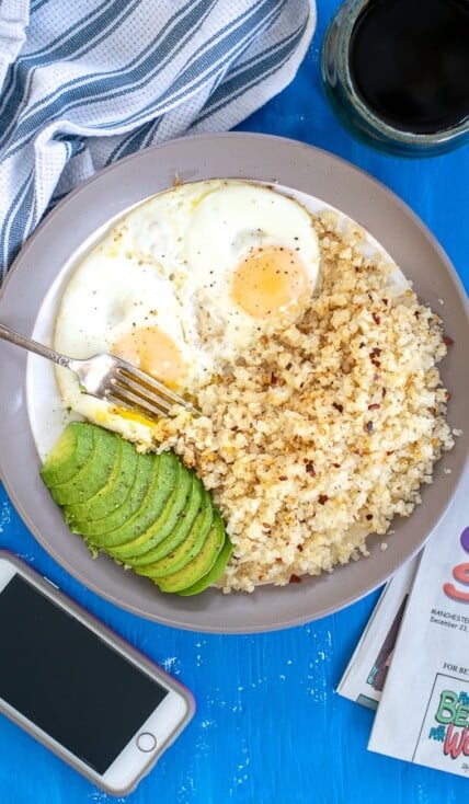 overhead shot of a plate full of breakfast eggs with cauliflower rice and avocado