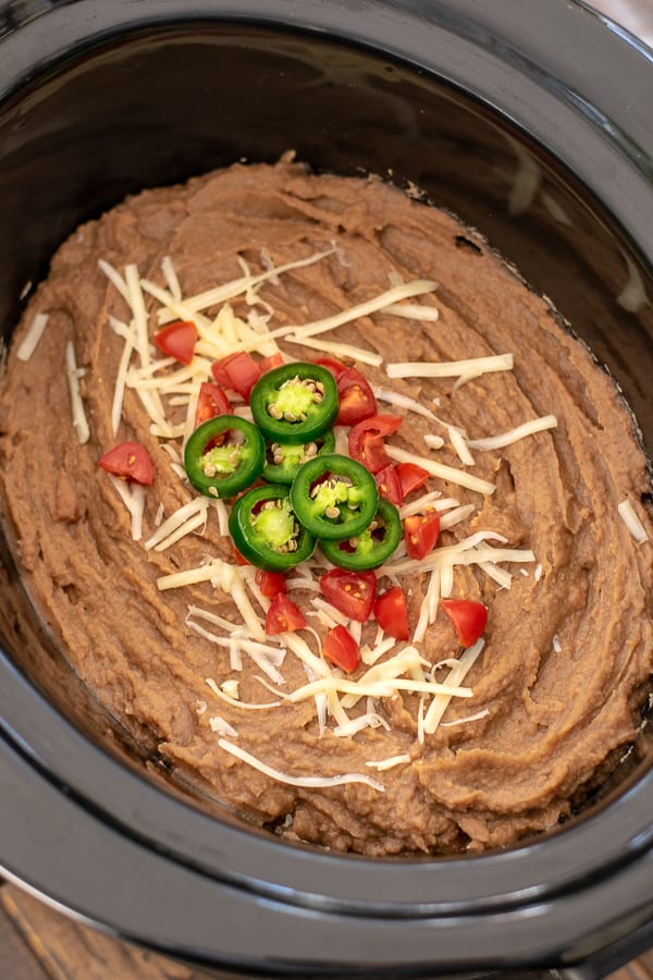 easy vegetarian refried beans in the crockpot with cheese, tomatoes, and jalapeños