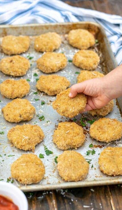 a toddler hand holding a baked chicken nugget