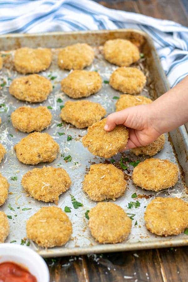 a toddler hand holding a baked chicken nugget