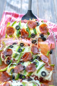 Supreme Pizza Chicken Bake Recipe Low Carb being served out of the dish pulling cheese and toppings with it