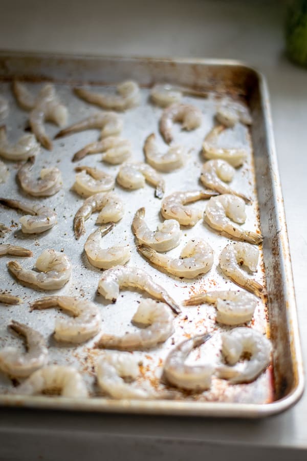 raw and cleaned shrimp on a sheet pan before cooking