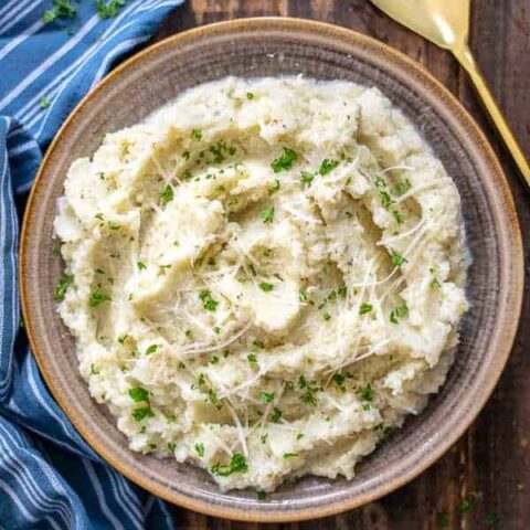 bowl of garlic parmesan mashed cauliflower on a wood table