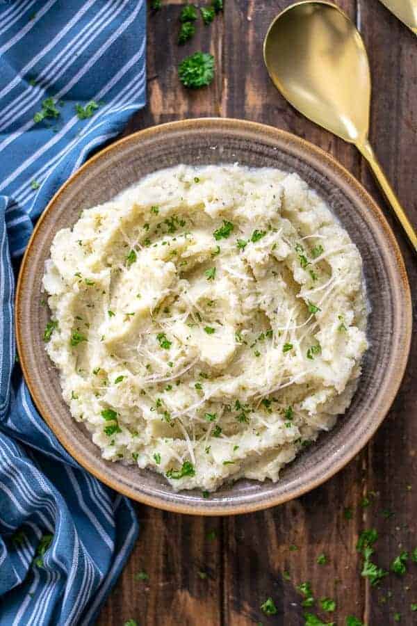 bowl of garlic parmesan mashed cauliflower on a wood table
