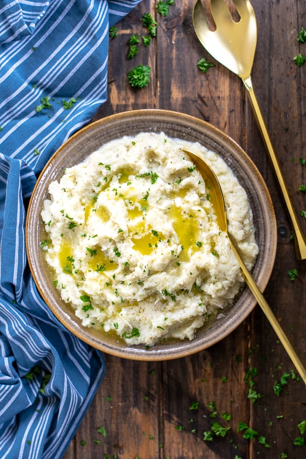 buttery cauliflower mash in a bowl with a gold spoon