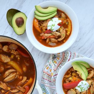 two bowls and a pot of chicken fajita soup on a table