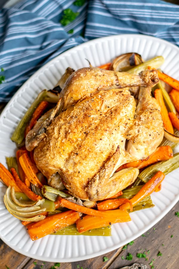 Easy Roast Chicken with Vegetables Recipe on a platter with a blue napkin roast chicken with vegetables | roast chicken and vegetables | roasted chicken with vegetables | roast chicken with vegetables in same pan | roast chicken over vegetables | how to roast chicken with vegetables | roast chicken on vegetables | roast chicken on vegetable bed | easy roast chicken and vegetables | easy roast chicken and vegetables recipe