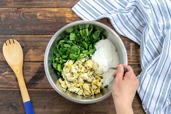 the spinach artichoke dip topping being stirred together for step 1