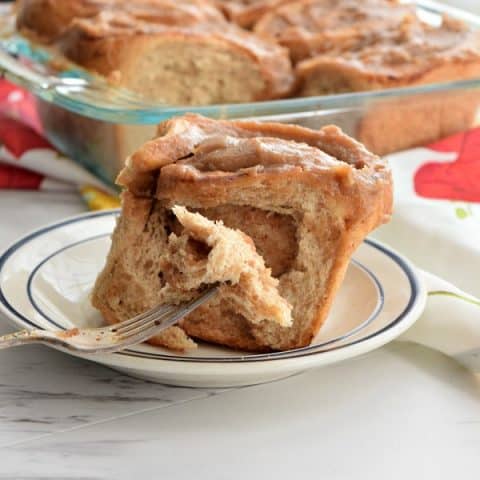 a fork taking a piece out of a date caramel roll on a plate
