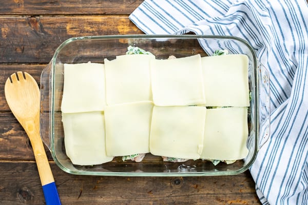 mozzarella cheese slices being put on top of the chicken bake
