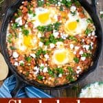 Overhead view of a shakshuka in a skillet on a table with parsley and feta
