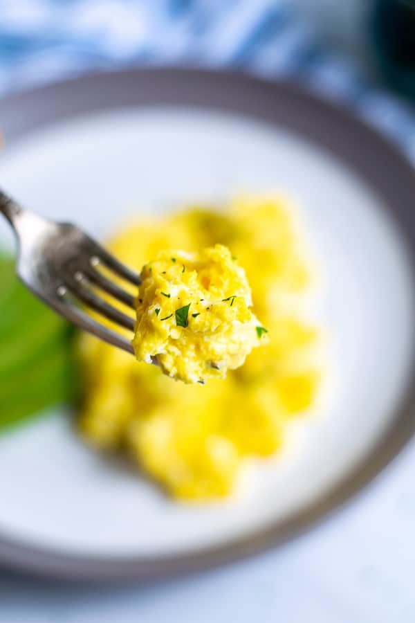 a fork with a bite of fluffy scrambled eggs on it