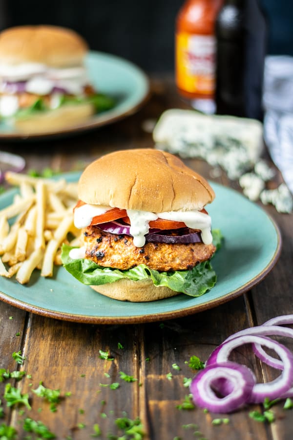chicken burger stuffed with buffalo and blue cheese on a teal plate with French fries