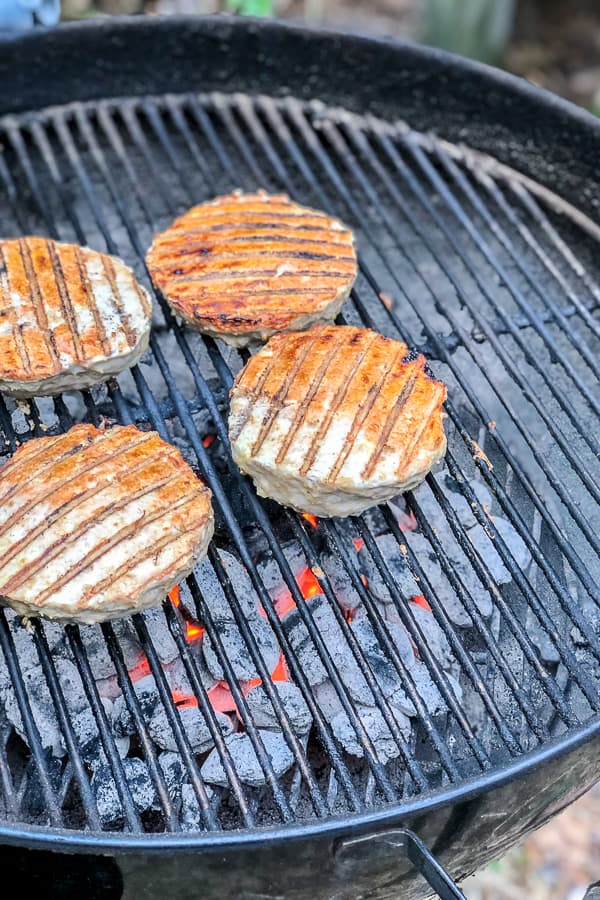 Stuffed Buffalo Chicken burgers cooking on a charcoal grill 