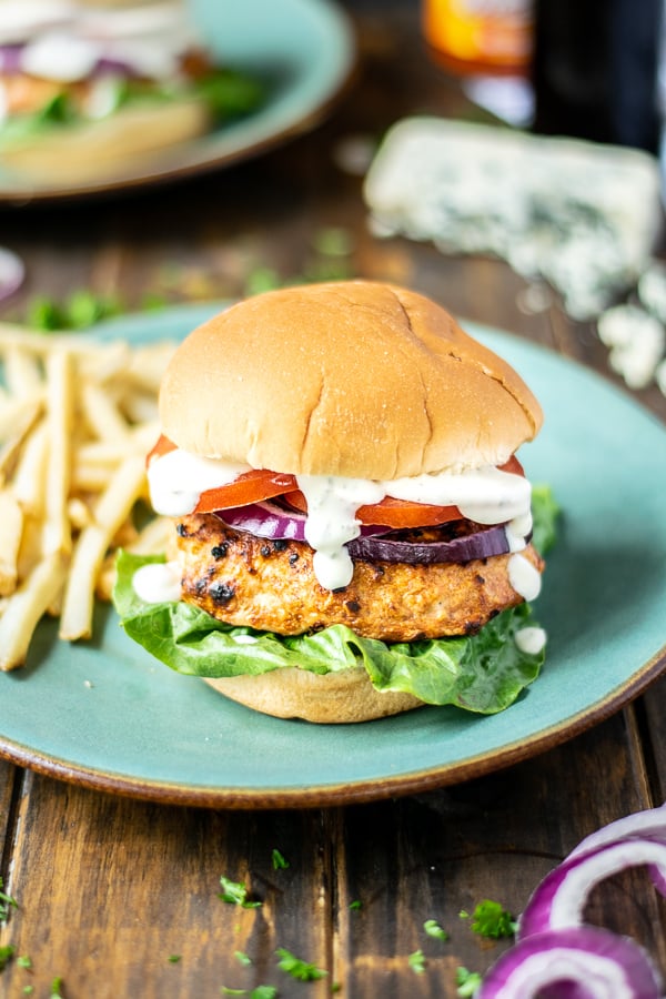 stuffed chicken burger on a teal plate with French fries