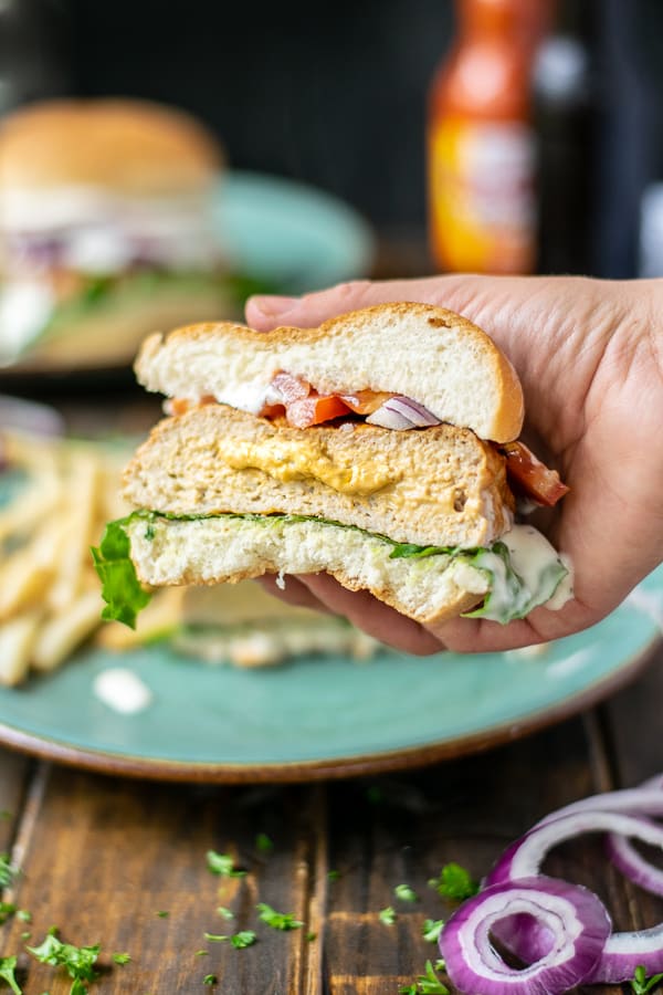 hand holding half a stuffed buffalo chicken burger showing filling