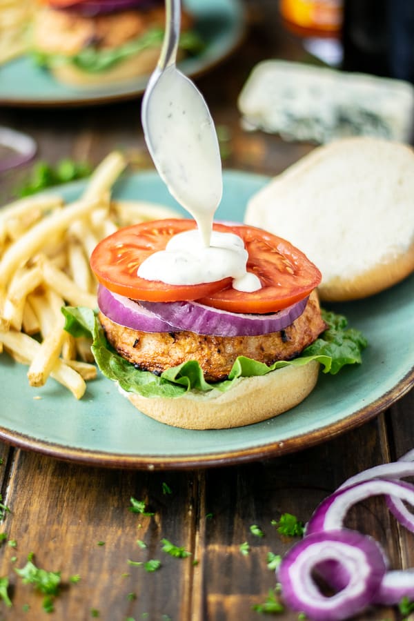 ranch dressing being drizzled on a buffalo chicken burger