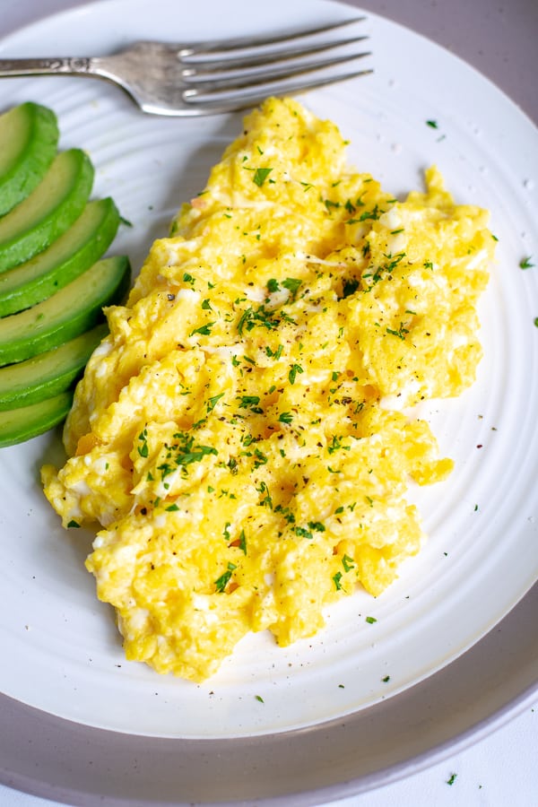scrambled eggs with salt, pepper, and parsley on a white plate