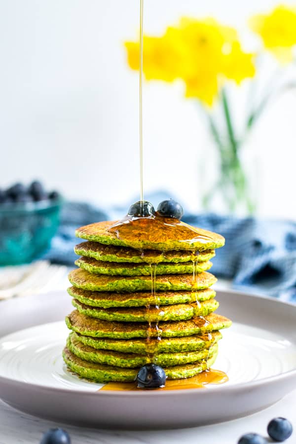 Maple Syrup being drizzled on a stack of green spinach pancakes