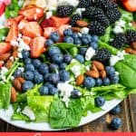 summer berry salad on a platter on a table covered in berries