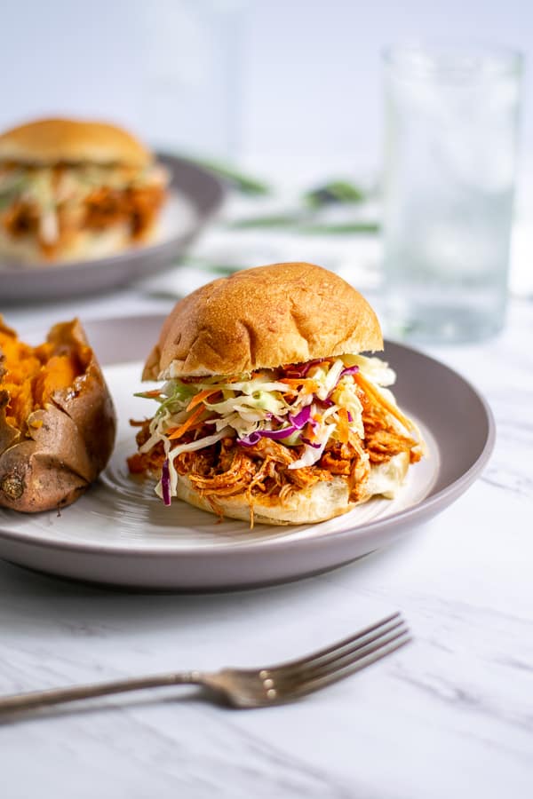 pulled chicken sandwich on a plate with a sweet potato