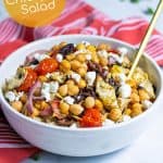 grilled chickpea salad with feta in a white bowl with tomatoes and artichokes