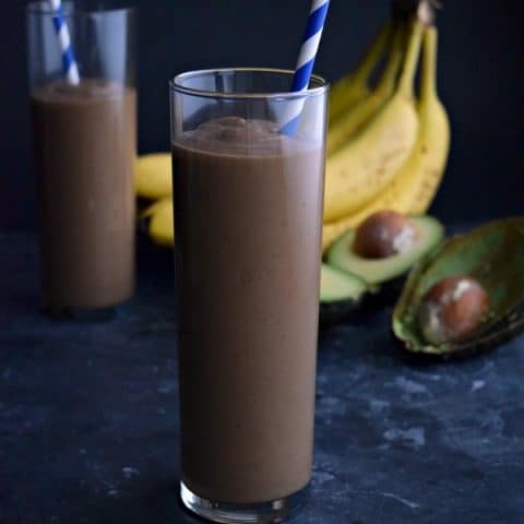 glass full of chocolate avocado smoothie with a blue straw
