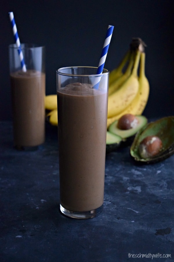 glass full of chocolate avocado smoothie with a blue straw