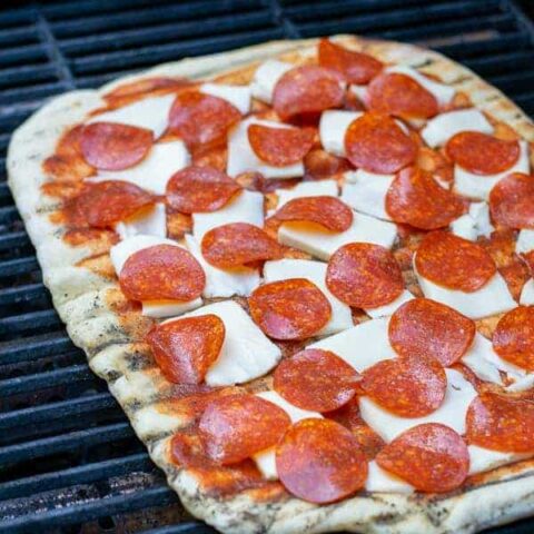 a pepperoni pizza on the grill cooking