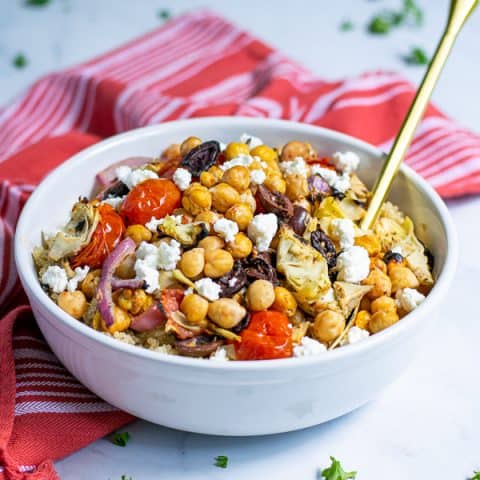 Healthy Chickpea Salad with Feta in a white bowl with a red napkin and gold spoon