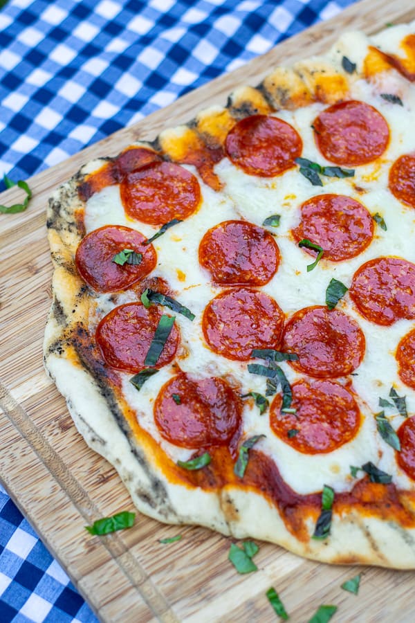 close up of a freshly grilled pizza on a cutting board