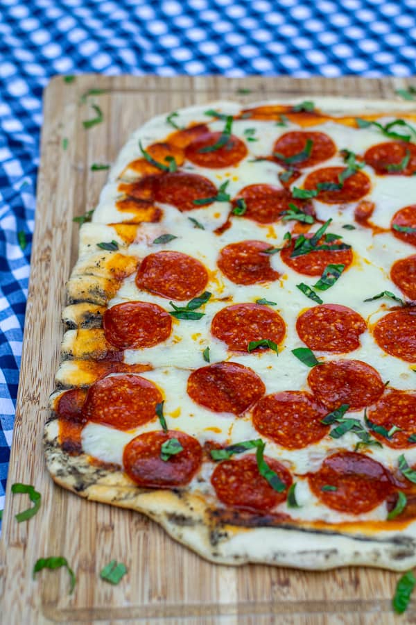 side shot of a grilled pizza on a cutting board