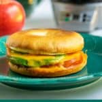 avocado tomato breakfast sandwich sitting on a teal plate