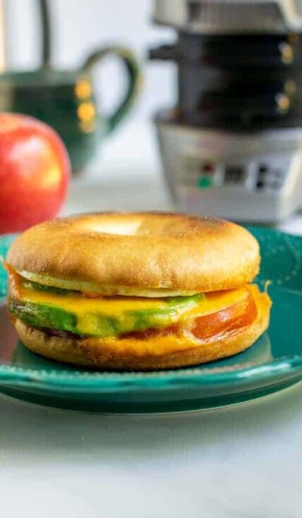 Avocado breakfast sandwich sitting on a teal plate.