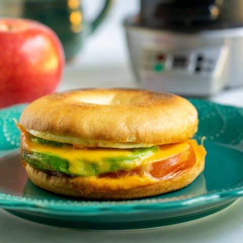 Avocado breakfast sandwich sitting on a teal plate.