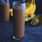 glass full of chocolate avocado smoothie with a blue straw