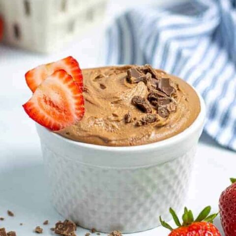 healthy best chocolate hummus in a white bowl sprinkled with chocolate shavings and slices of strawberries
