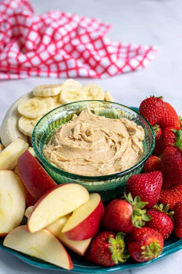 Platter with peanut butter fruit dip surrounded by cut up fruit.