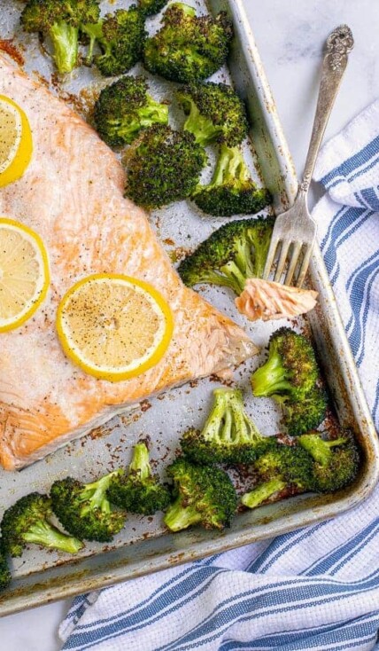 Forkful of baked salmon with broccoli on a sheet pan.