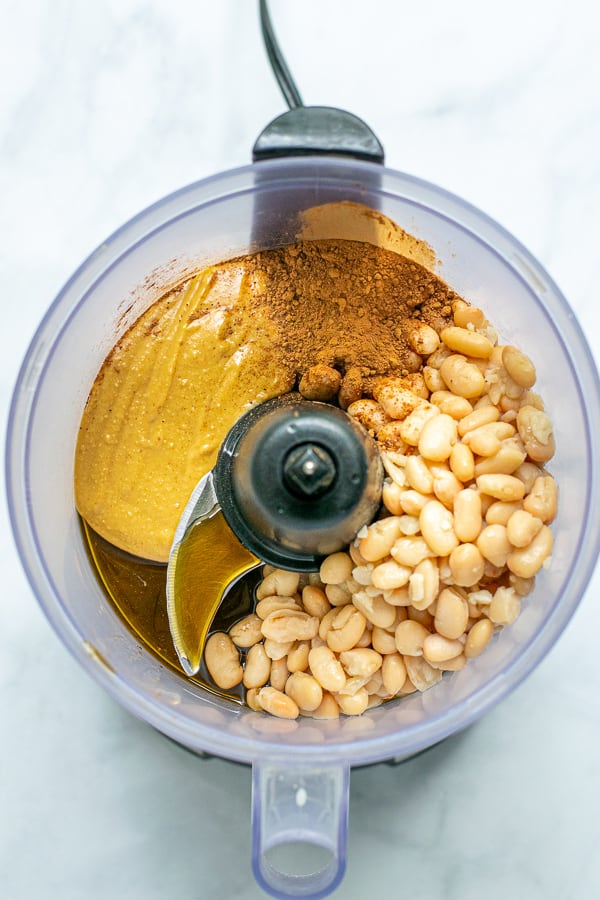ingredients in a food processor ready to be blended into hummus