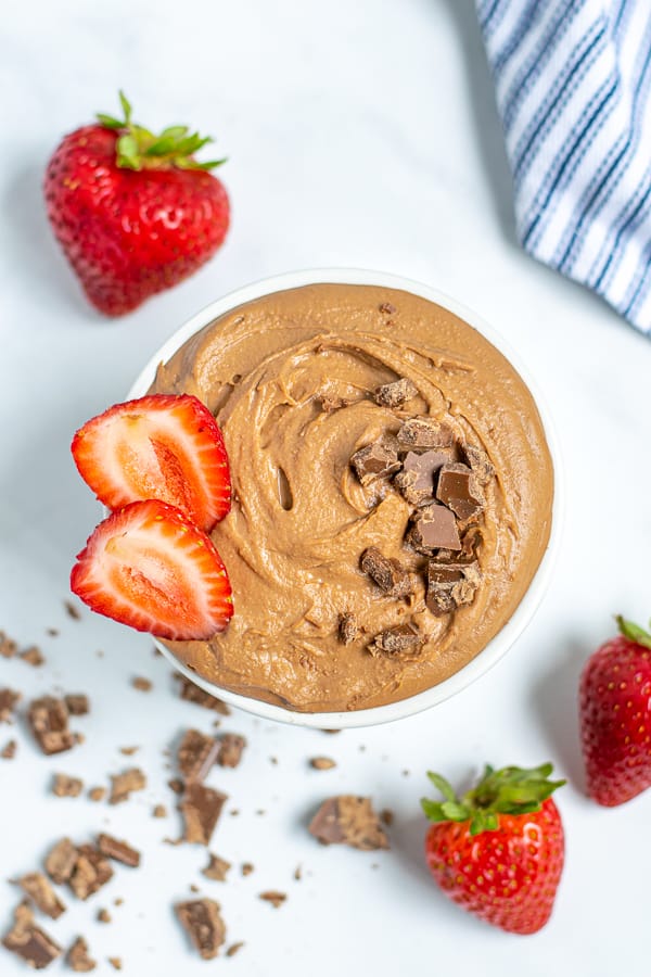 overhead shot of a bowl of chocolate hummus with chocolate shavings and strawberries