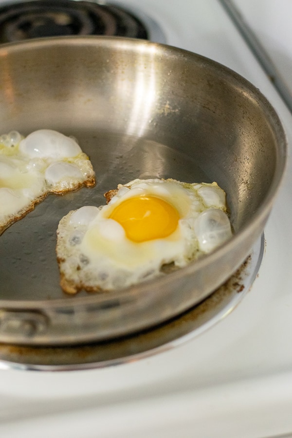 close up a an egg coking in a frying pan on a stove