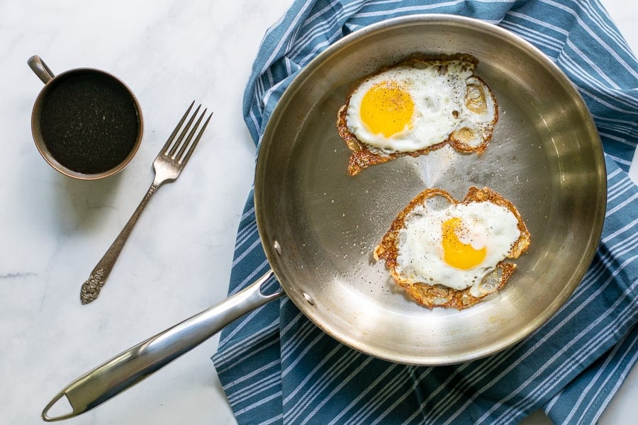 overhead photo of a stainless steel frying pan with two fried eggs in it