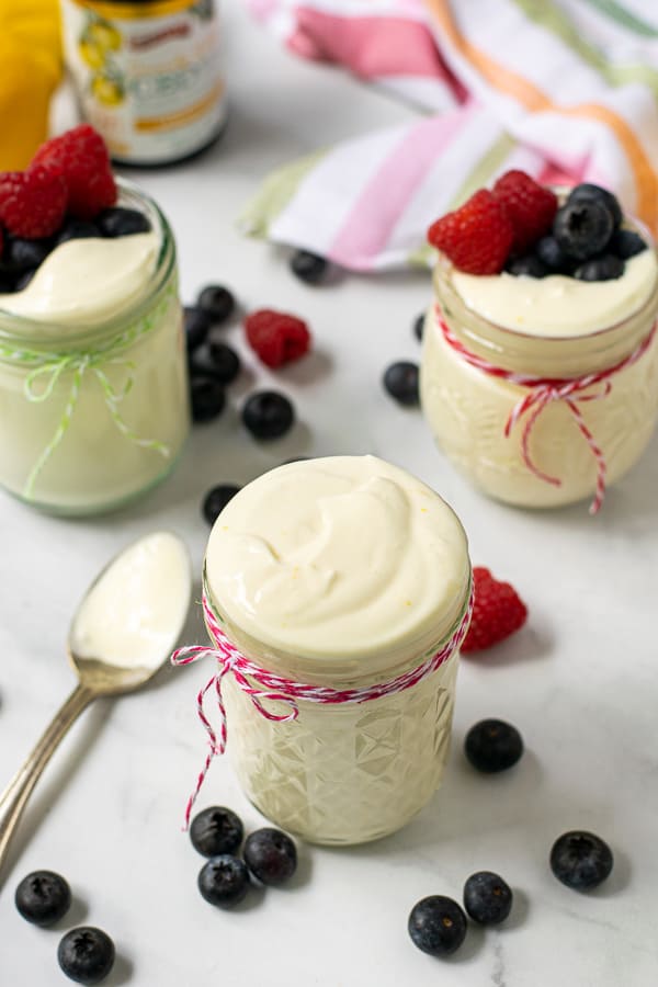 jars on a table filled with lemon whipped greek yogurt and berries