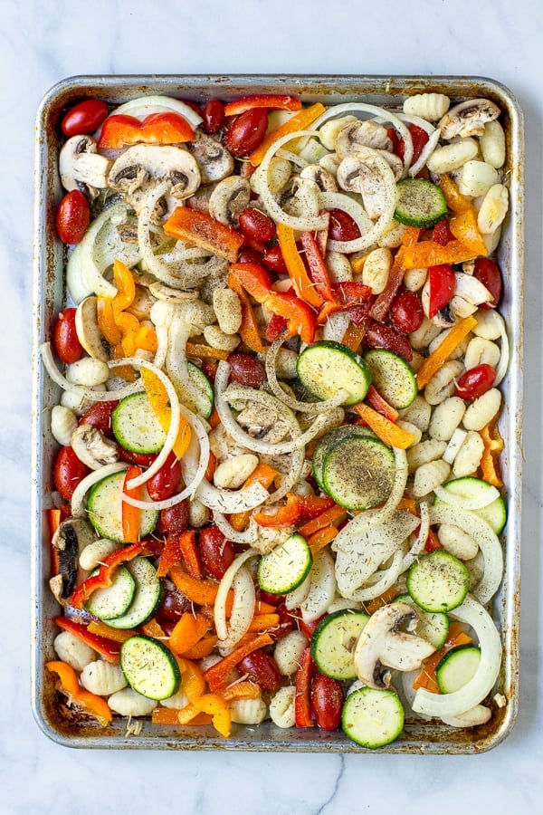 tossed vegetables and gnocchi on a sheet pan before cooking