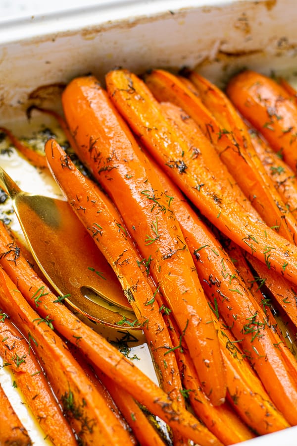 close up of roasted carrots with dill in a roasting pan