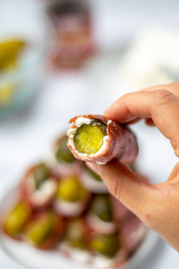 single pickle roll up with a bite out of it in a hand