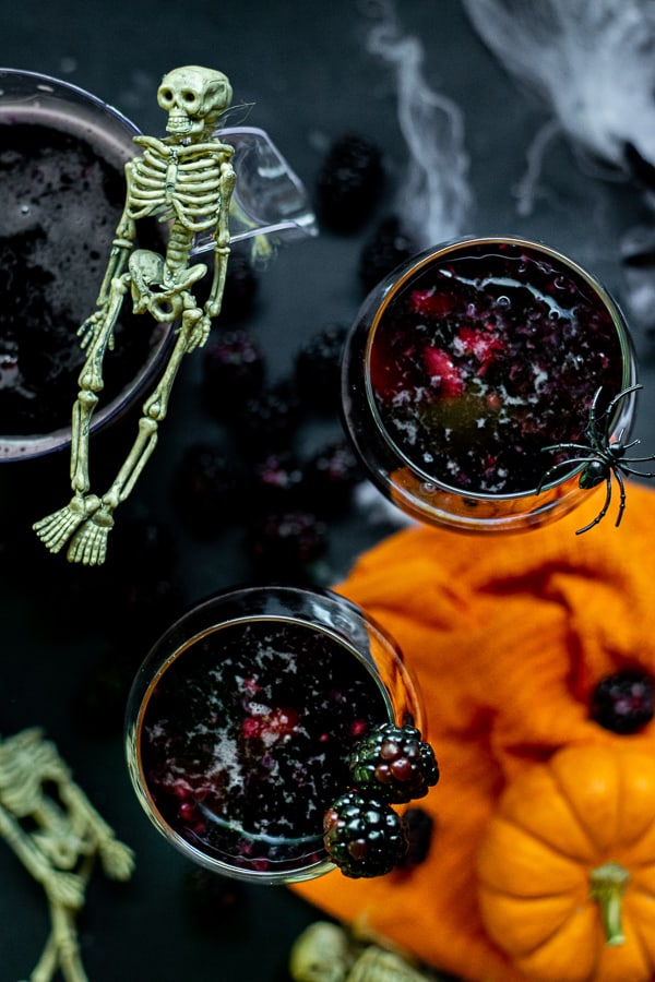 wine glasses full of black fruit and halloween sangria on a black table