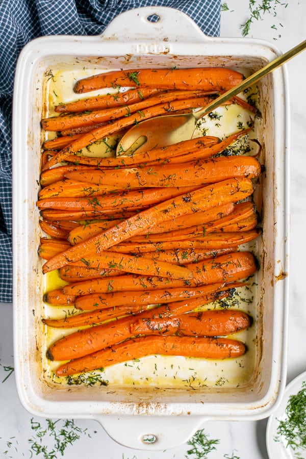 roasted carrots in a white baking dish sprinkled with fresh dill