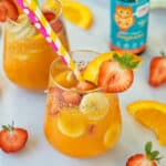 glass filled with fruit and orange juice with colorful straws